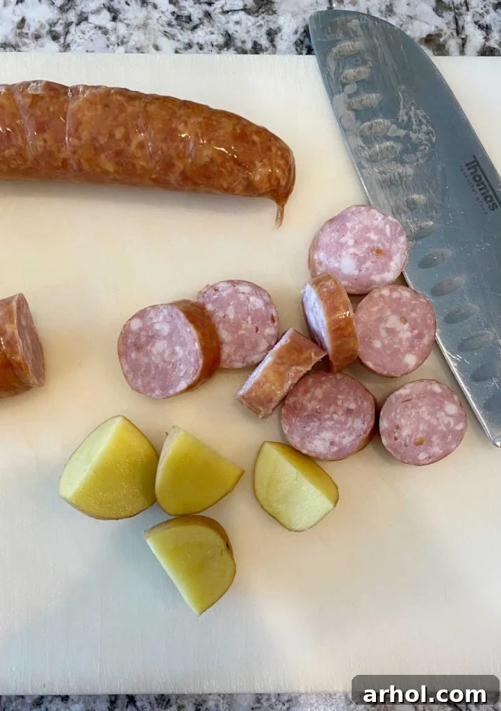 Sliced smoked sausage and quartered baby potatoes laid out on a cutting board, ready for the slow cooker.