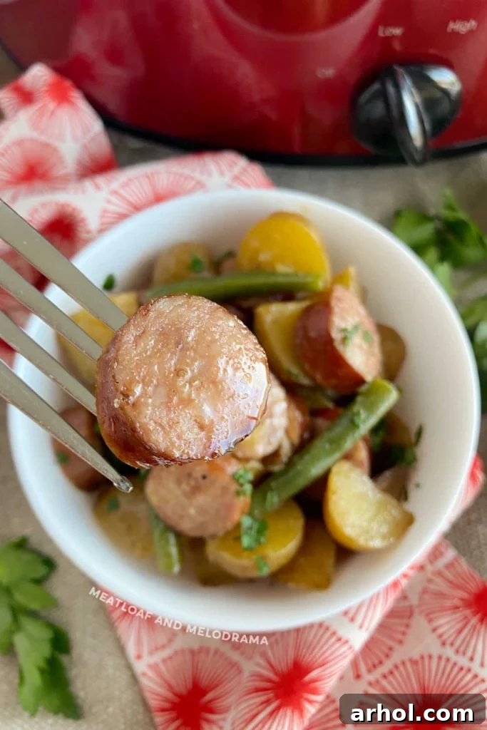 A slice of cooked kielbasa sausage on a fork, showing its juicy texture.