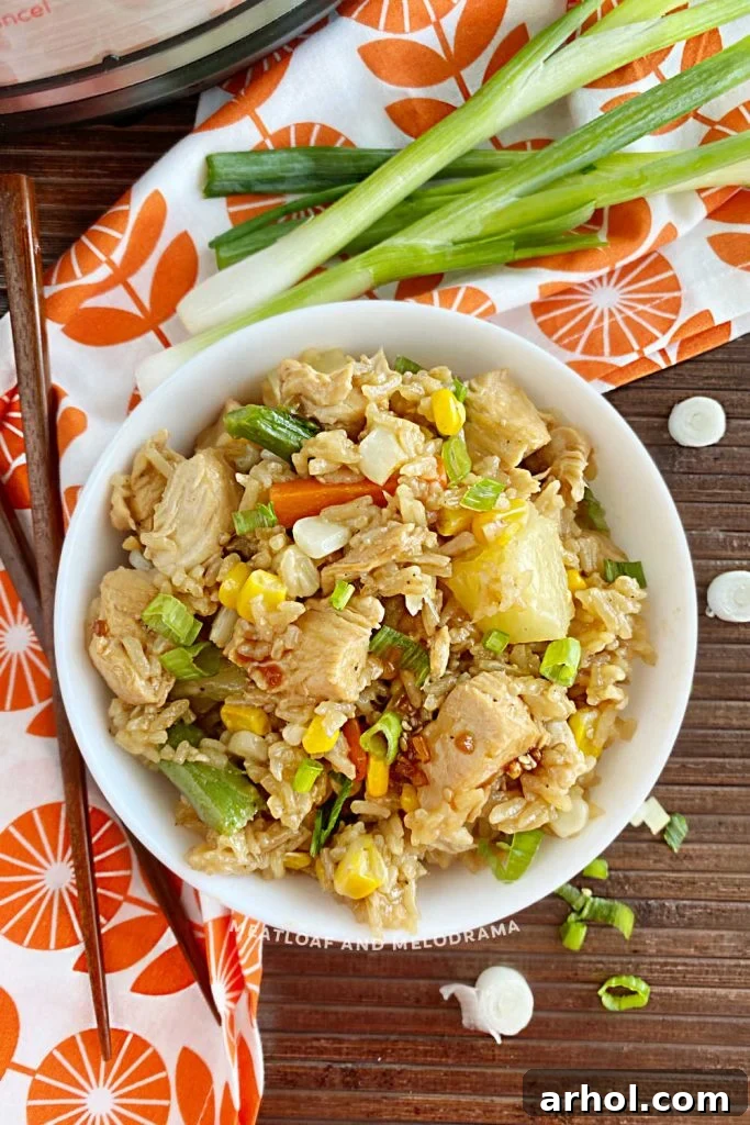A delectable bowl of Instant Pot Teriyaki Chicken and Rice, garnished with green onions, ready to be enjoyed. An Instant Pot and chopsticks are visible in the background.