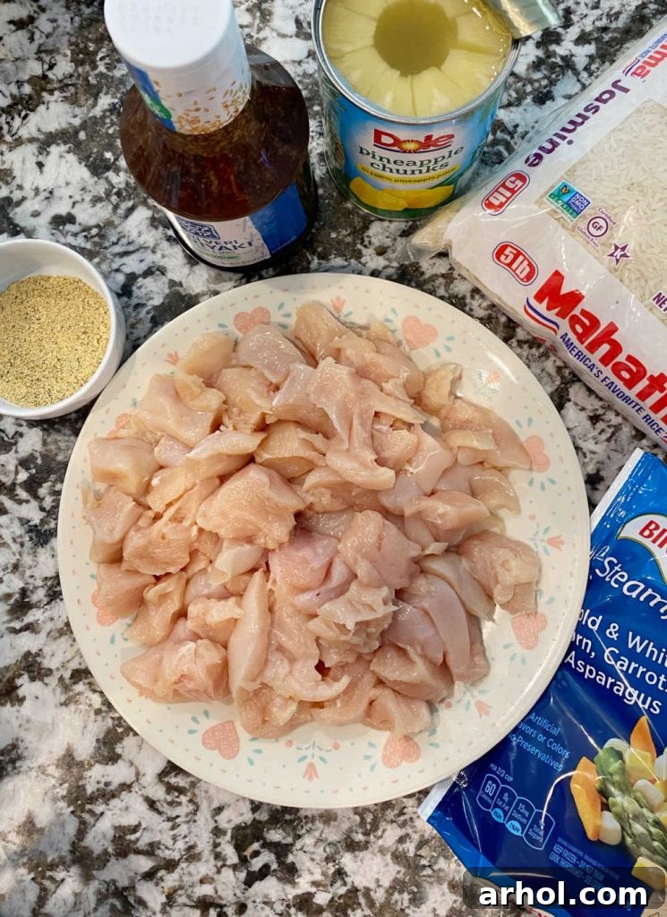 Assortment of fresh ingredients for Instant Pot Teriyaki Chicken and Rice bowls laid out on a table, including chicken, rice, vegetables, and sauce.