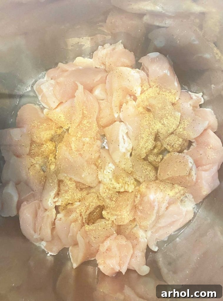 Close-up of chicken breast pieces being sautéed in an electric pressure cooker pot, turning golden brown.