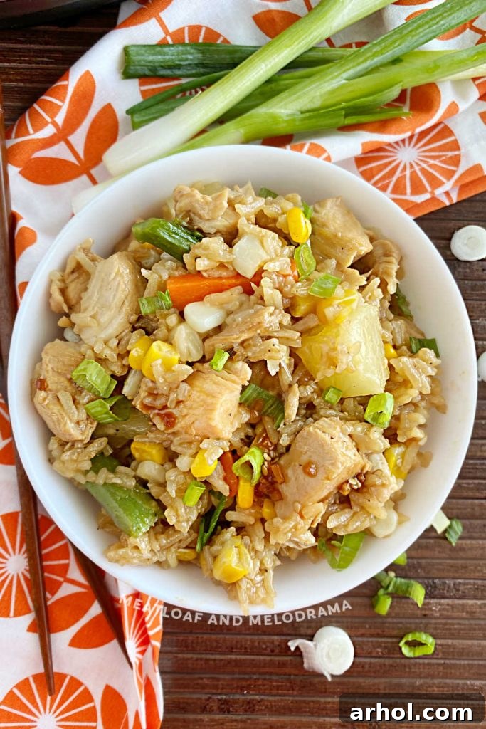 A bowl of Instant Pot teriyaki chicken and rice, garnished and ready to serve, placed on a wooden table.