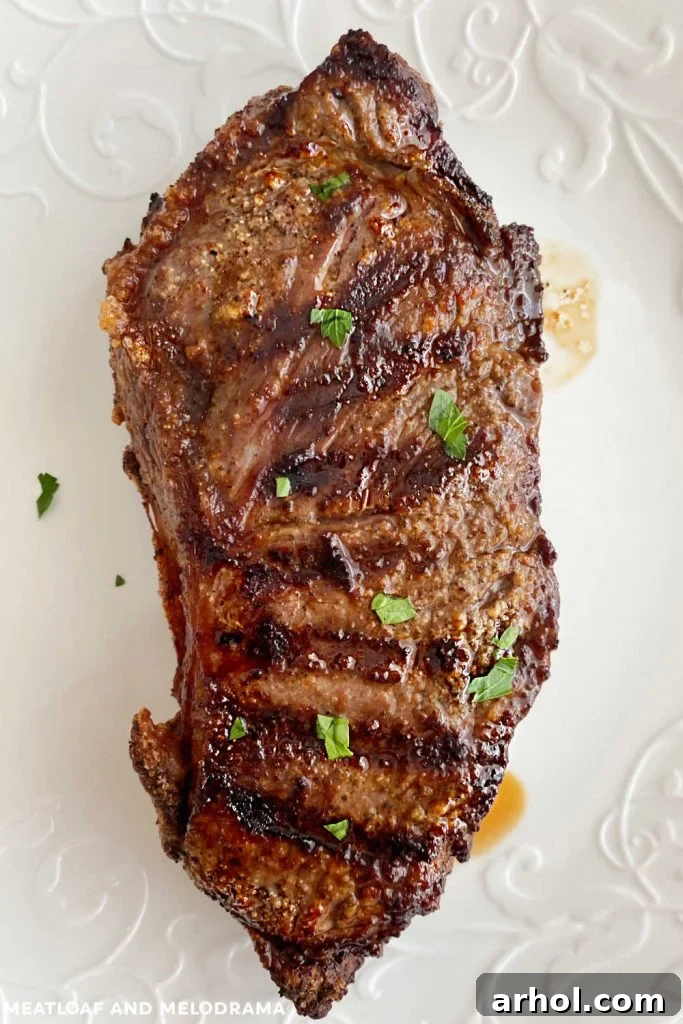 Grilled New York strip steak with fresh parsley and distinct grill marks, cooked on a Ninja Foodi XL indoor grill, presented on a pristine white plate.