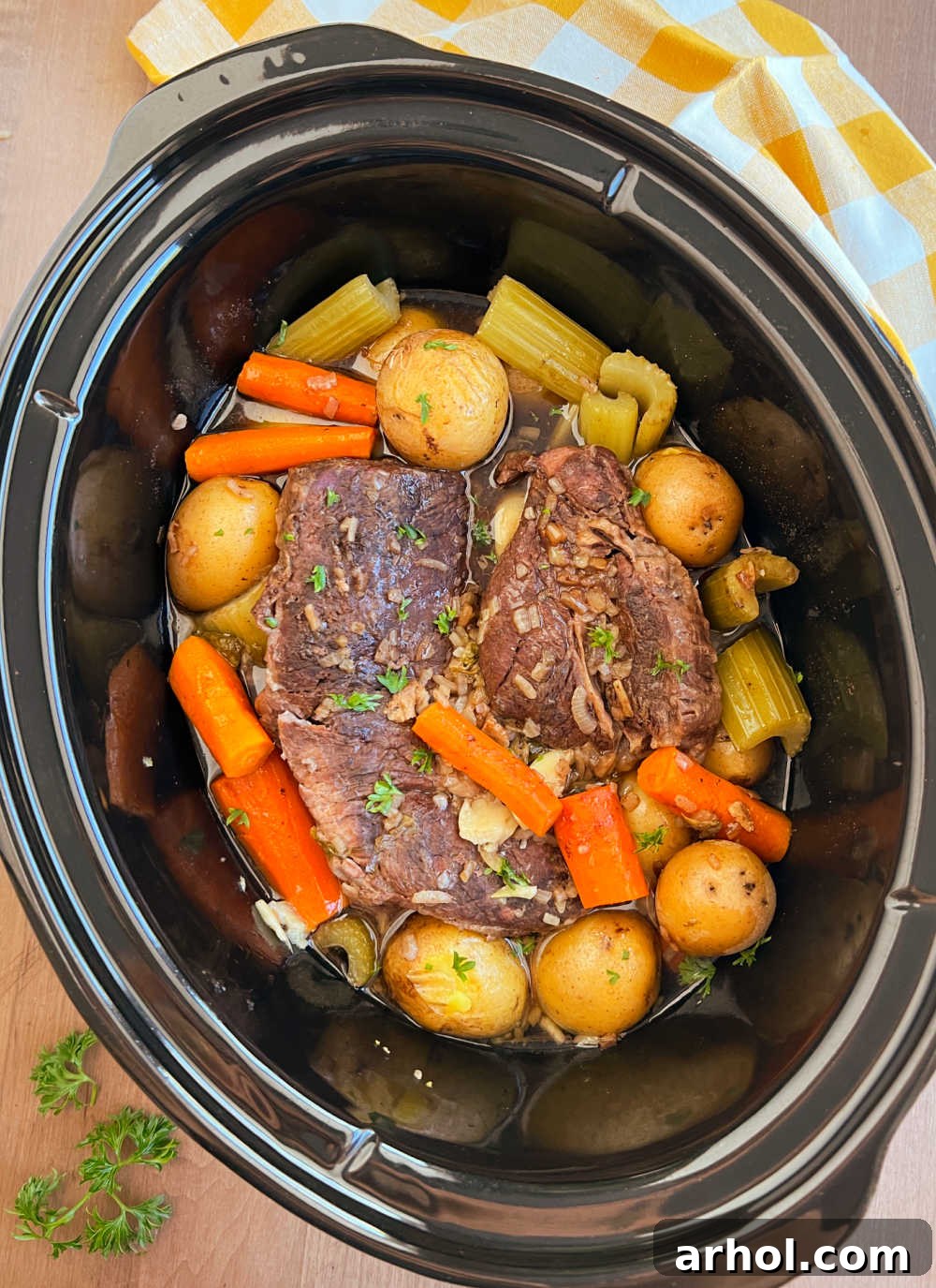 Slow cooker pot roast with onion soup mix, potatoes and carrots cooking until fork tender and delicious.