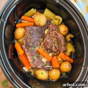 Slow cooker pot roast with onion soup mix, potatoes and carrots in crock pot.
