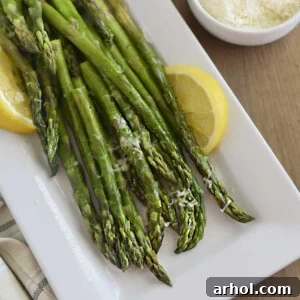 microwave asparagus on white platter with lemon slices and parmesan cheese