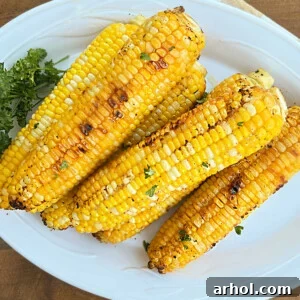 grilled corn on the cob in foil with parsley on platter
