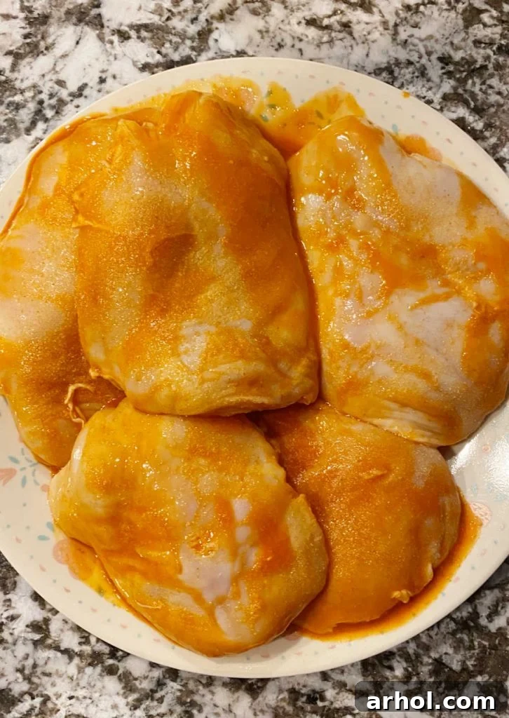 Boneless chicken breasts marinating in spicy Buffalo sauce on a plate