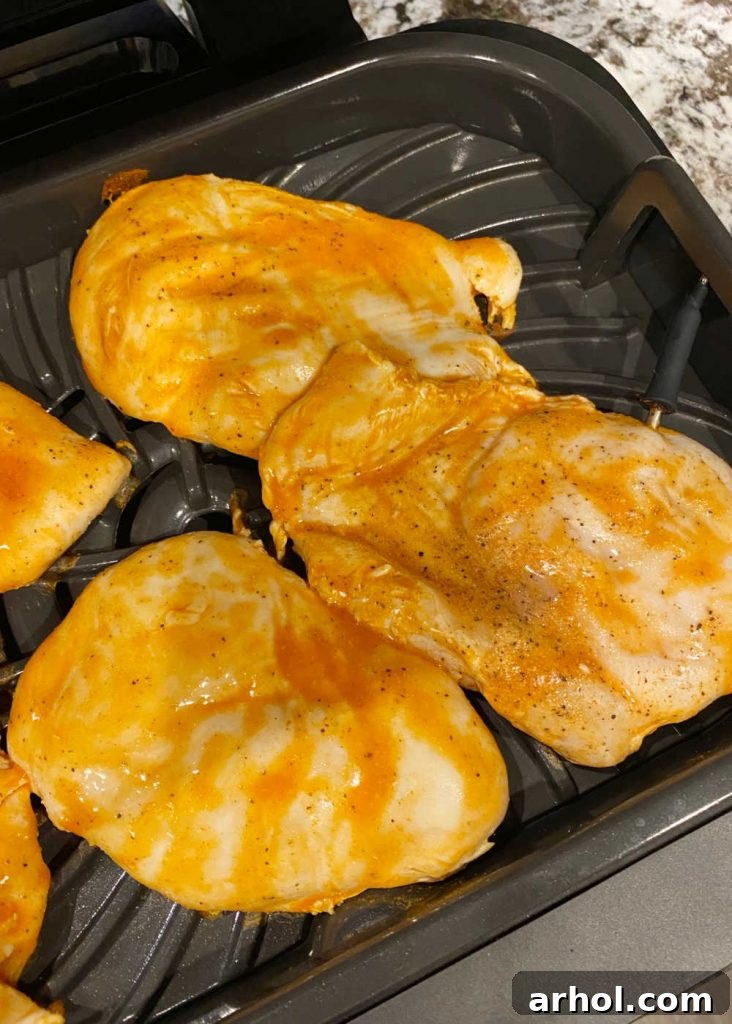 Buffalo sauce-coated chicken breasts grilling on a Ninja Foodi Grill