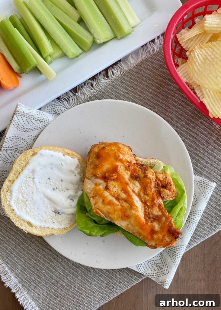 Grilled chicken breast with red hot sauce, ranch dressing, and lettuce on a bun