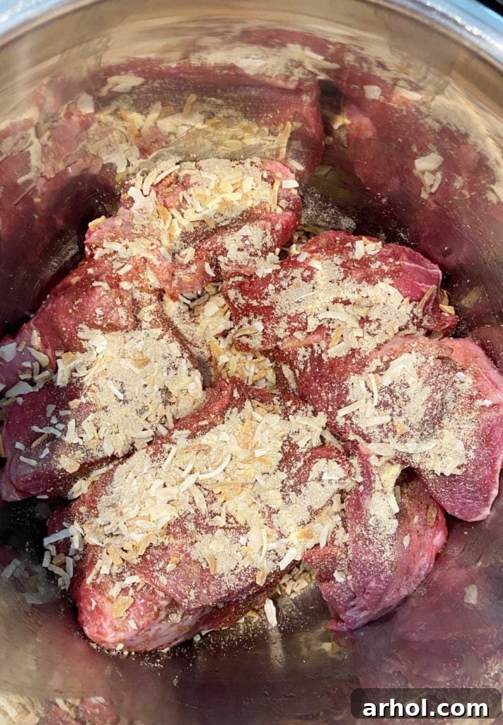Beef chuck roast with dry onion soup mix, beef broth, and seasonings arranged in the Instant Pot