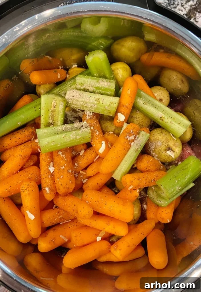 Chuck roast, onion soup mix, baby potatoes, carrots, and celery layered inside the Instant Pot pressure cooker