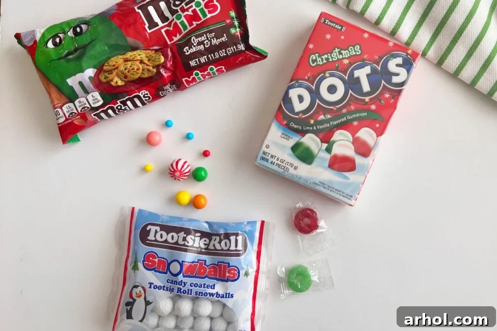 Assortment of colorful candies including M&Ms, Dots, and snowball candies for gingerbread house decorating