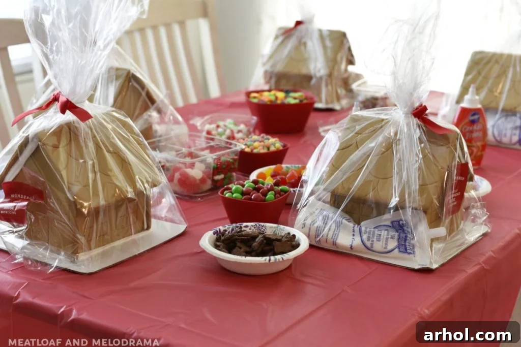 Undecorated gingerbread houses arranged on a table with bowls of candy