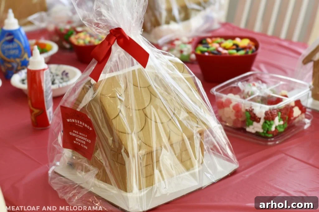 Close-up of a gingerbread house decorating party setup with various candies and icing