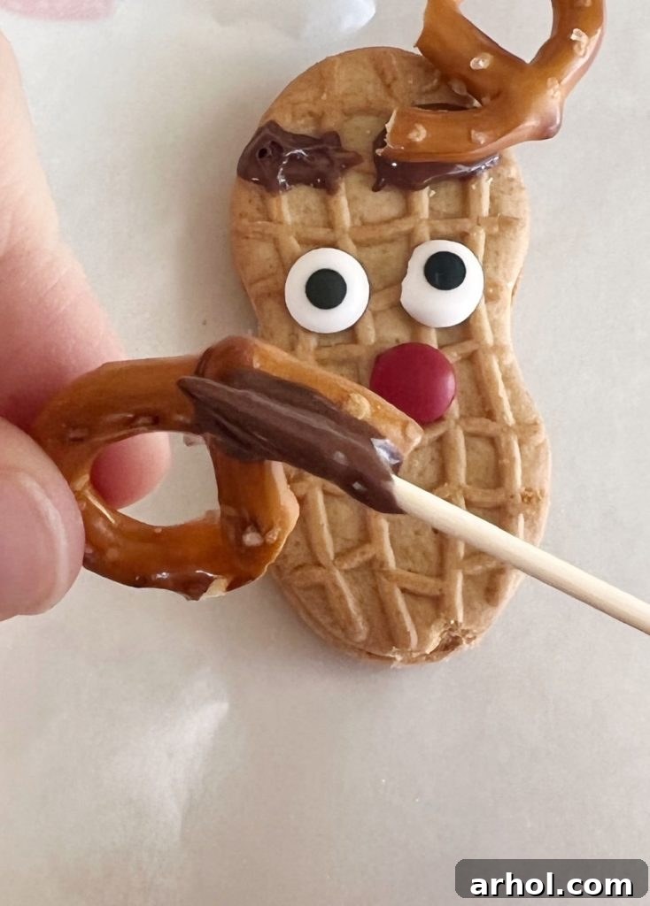 melted chocolate on pretzel antler for reindeer cookie