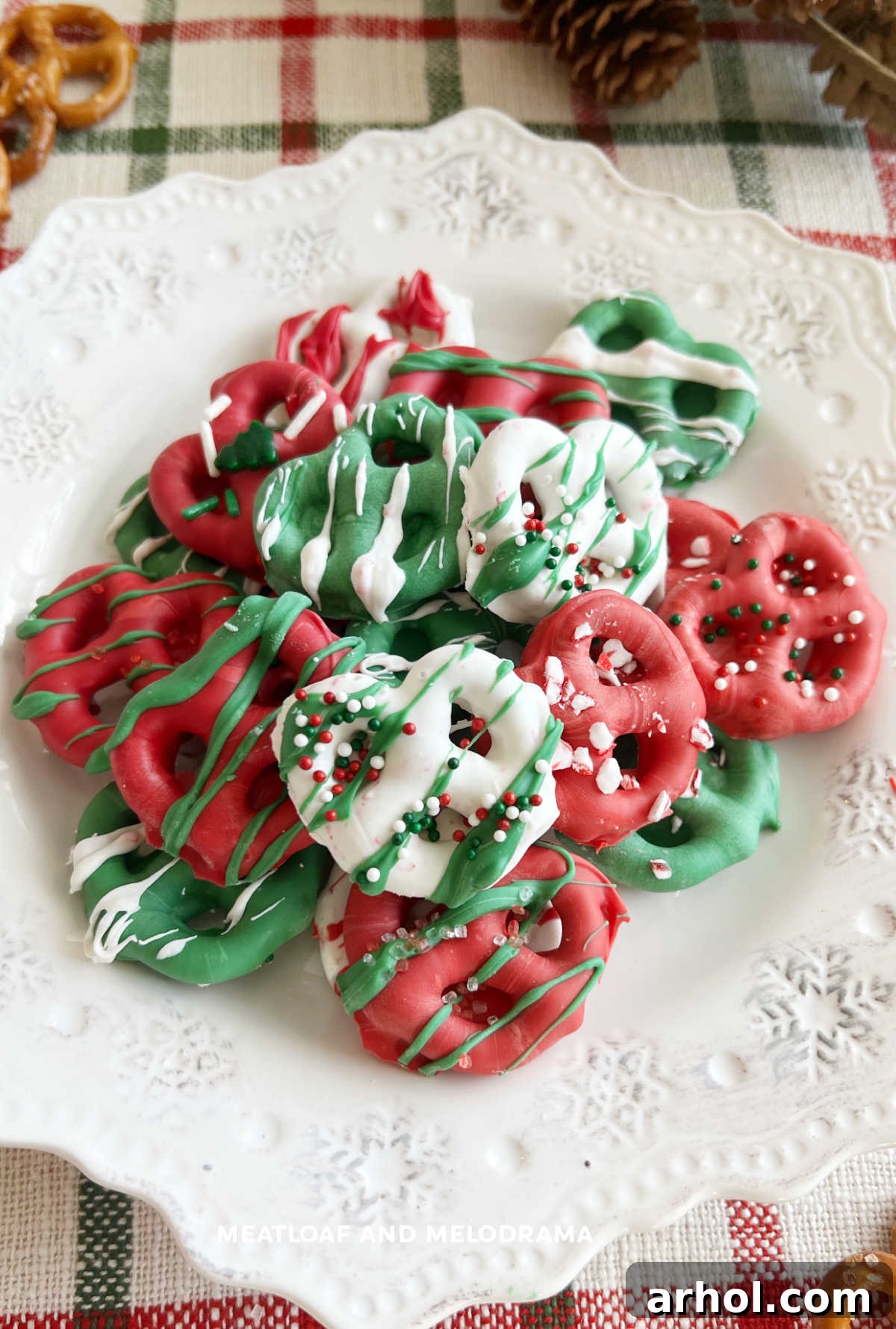 A beautifully arranged plate of chocolate dipped Christmas pretzels, generously coated and decorated with holiday sprinkles, ready for serving.