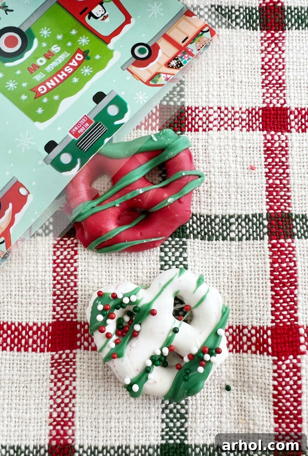 Red and white chocolate covered pretzels with sprinkles, neatly packed in a cellophane treat bag with a festive ribbon, ready for gifting.