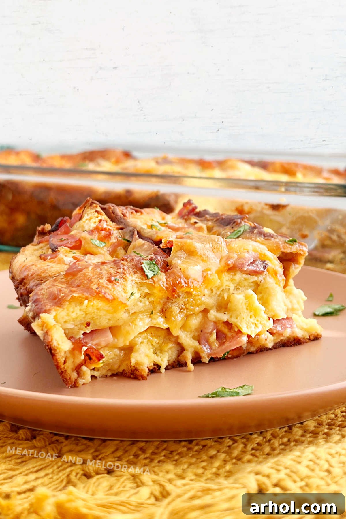 slice of ham and cheese breakfast strata on the table with parsley