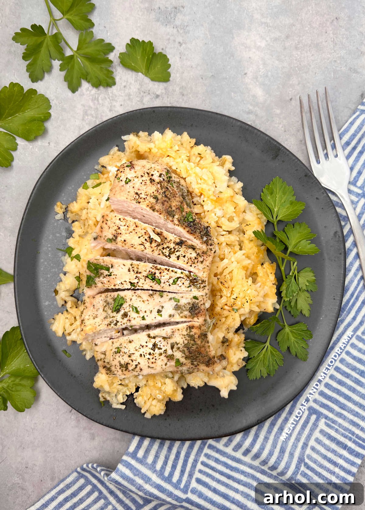 Golden-brown no peek chicken and rice served on a black plate, garnished with fresh parsley.