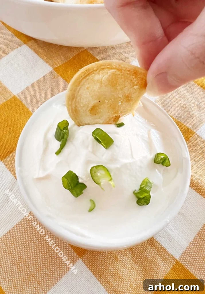 hand dipping air fried pierogi in sour cream