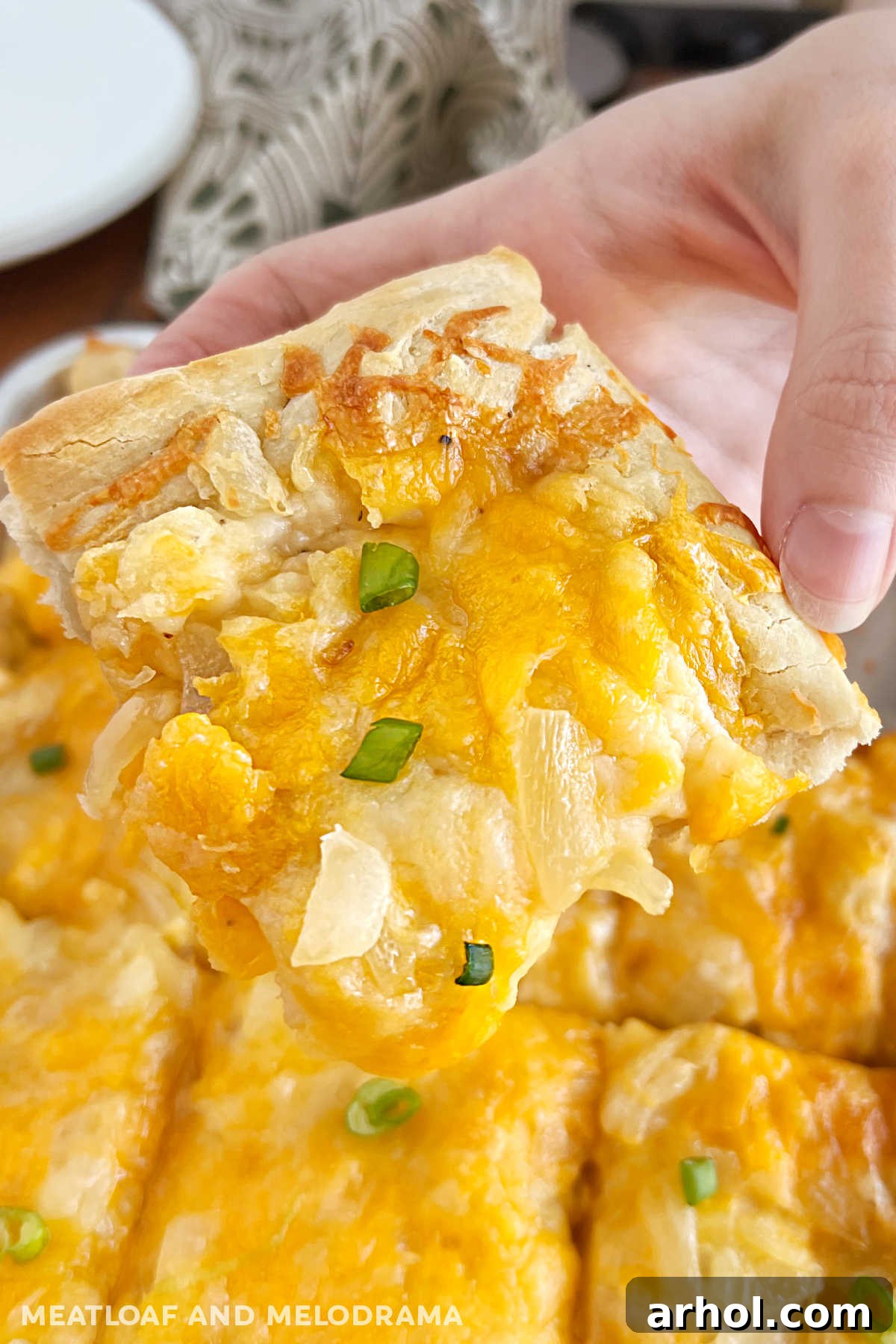 slice of pierogi pizza (pagach) with onions in hand