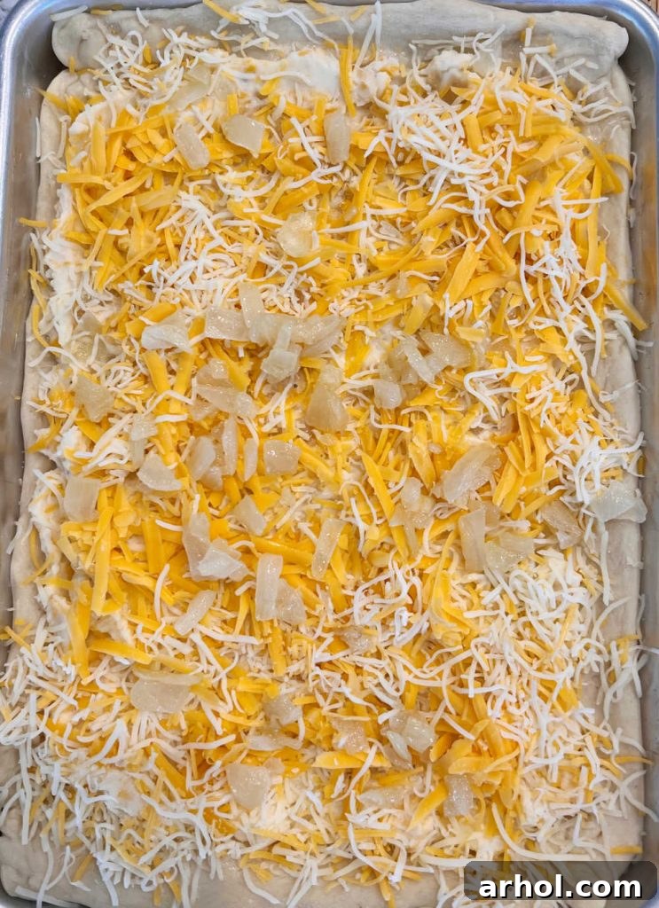 unbaked pierogi pizza with mashed potatoes, cheese and onions on baking sheet