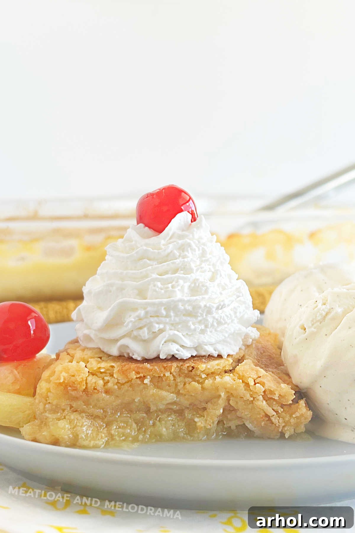 slice of pineapple dump cake with ice cream, whipped cream and maraschino cherries