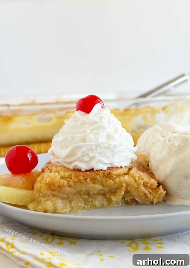 slice of pineapple dump cake with ice cream and maraschino cherries on a plate
