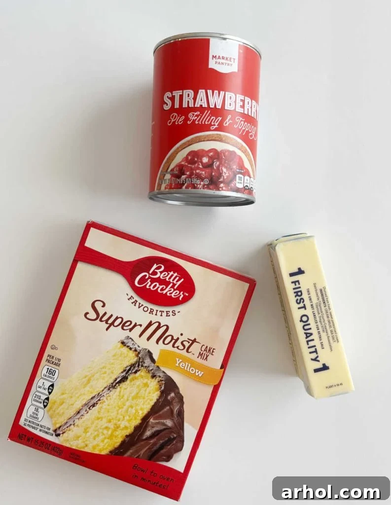 The three core ingredients for strawberry dump cake laid out on a table: dry yellow cake mix, two cans of strawberry pie filling, and sticks of butter.