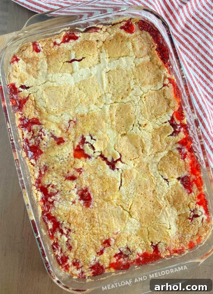 A beautifully baked strawberry dump cake, golden brown and bubbly, sitting on a kitchen counter, ready to be served.