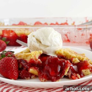 A delicious slice of strawberry dump cake showing the layers of filling and cake, garnished with fresh strawberries and a dollop of ice cream.