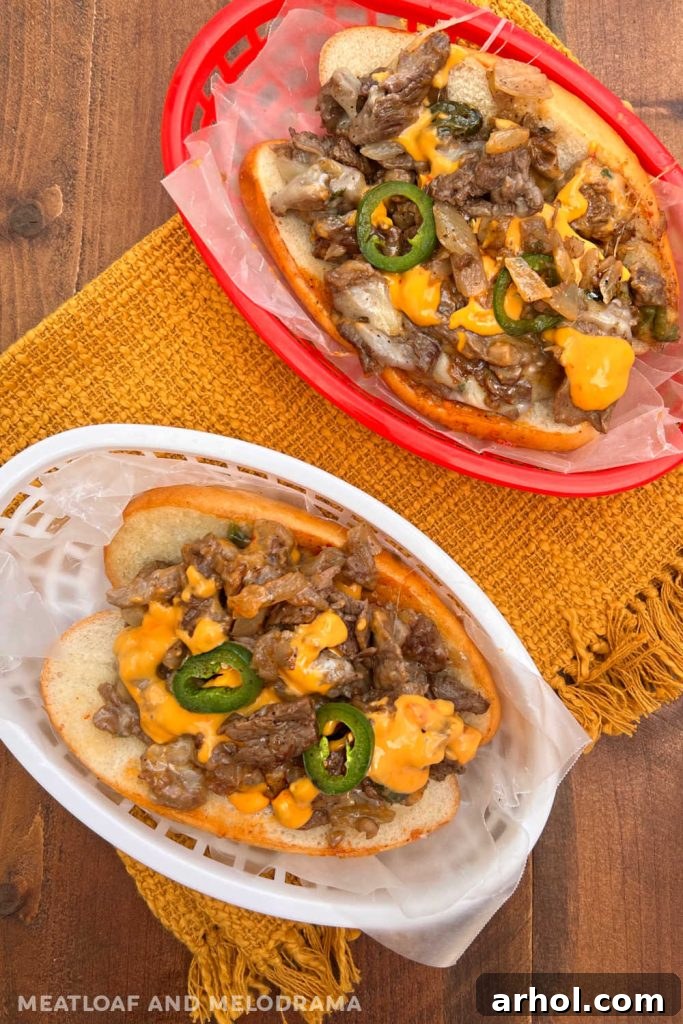 Two Arizona style cheesesteaks made on a Blackstone griddle, served with a side of nacho cheese on a table, showcasing the delicious combination of steak, peppers, and cheese.