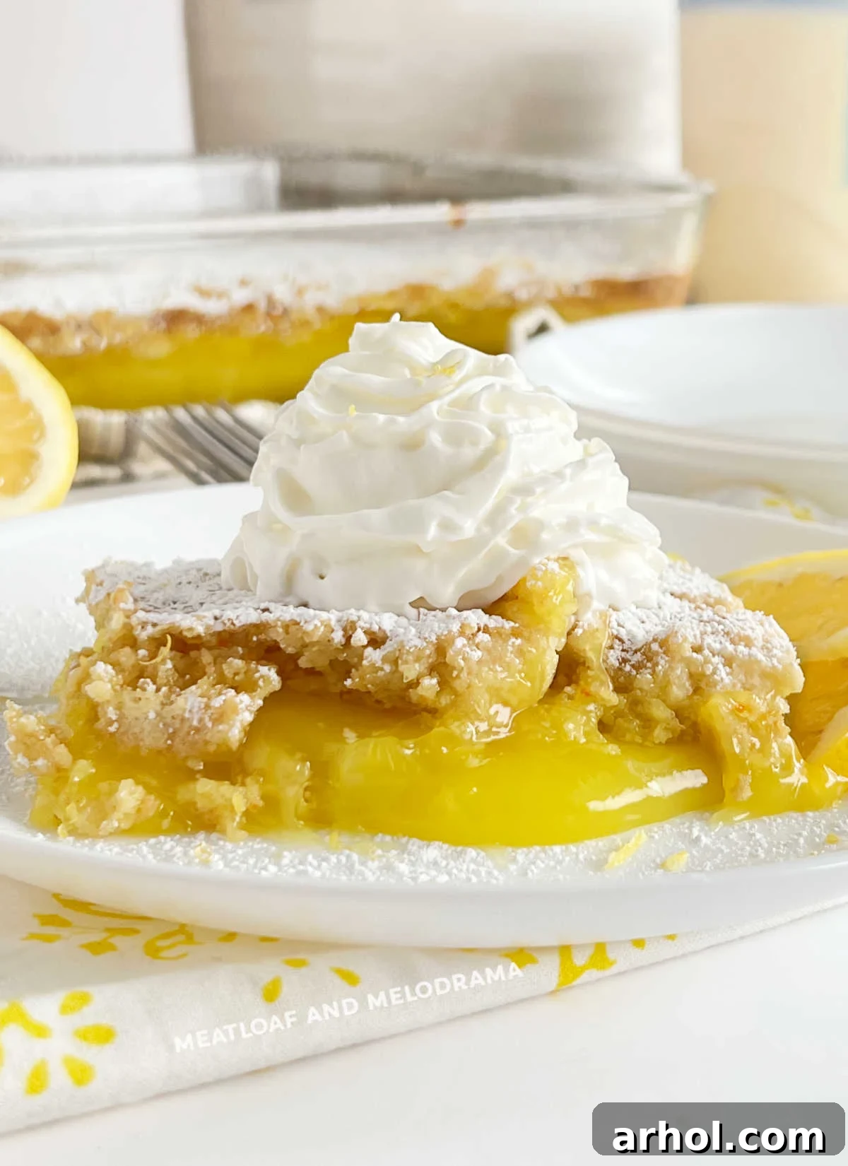 Refreshing Lemon Dump Cake with Whipped Cream A slice of lemon dump cake with a dollop of whipped cream on a white plate, ready to be enjoyed.