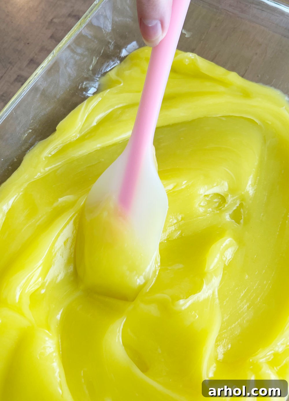 Lemon Pie Filling Layer Smooth lemon pie filling evenly spread in a baking pan with a spatula.