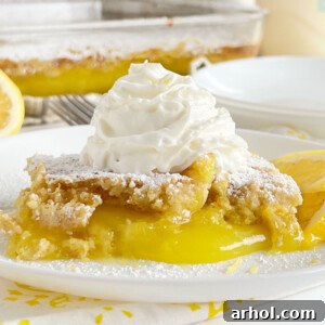 A baked lemon dump cake topped with whipped cream, served on a table.