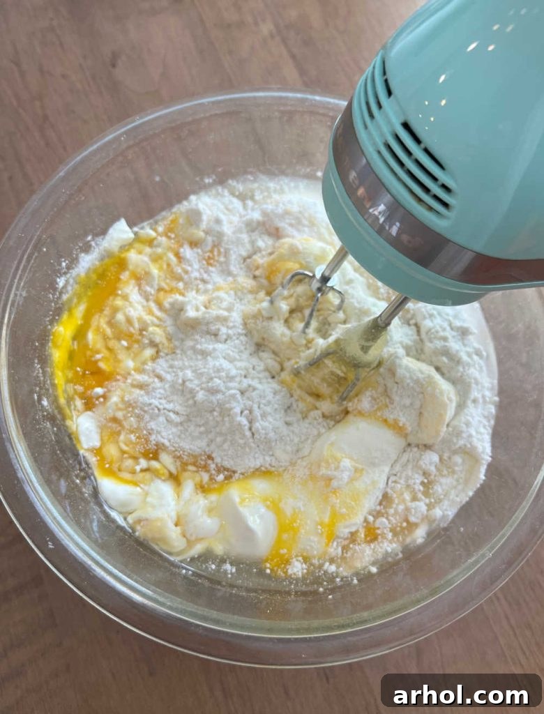 Irresistible Easter Lamb Cake 5 Thick pound cake batter being mixed in a large bowl with an electric mixer, showing the creamy consistency