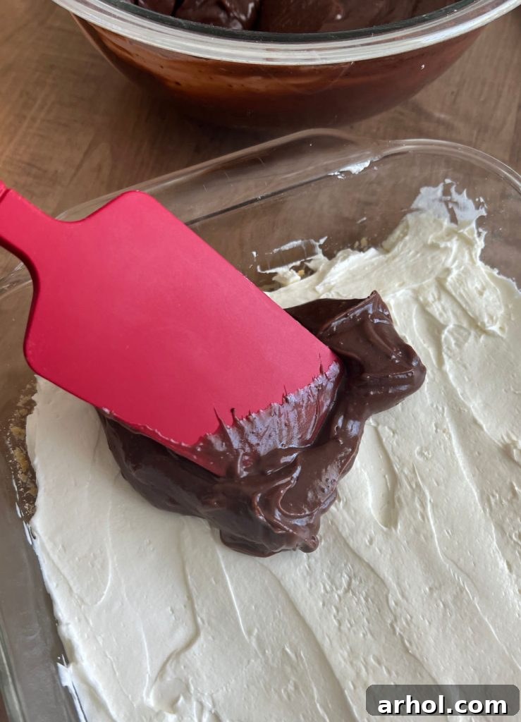 Carefully spreading the instant chocolate and vanilla pudding mixture over the chilled cream cheese layer.