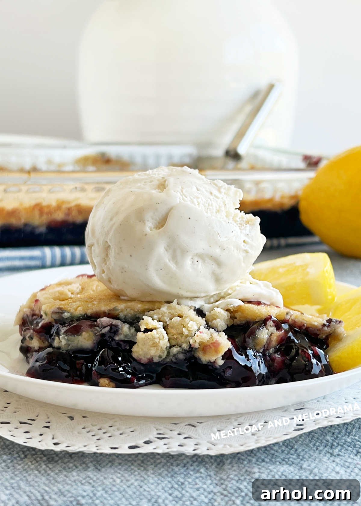 Blueberry dump cake dessert on a plate with vanilla ice cream and lemon slices, ready to be enjoyed.