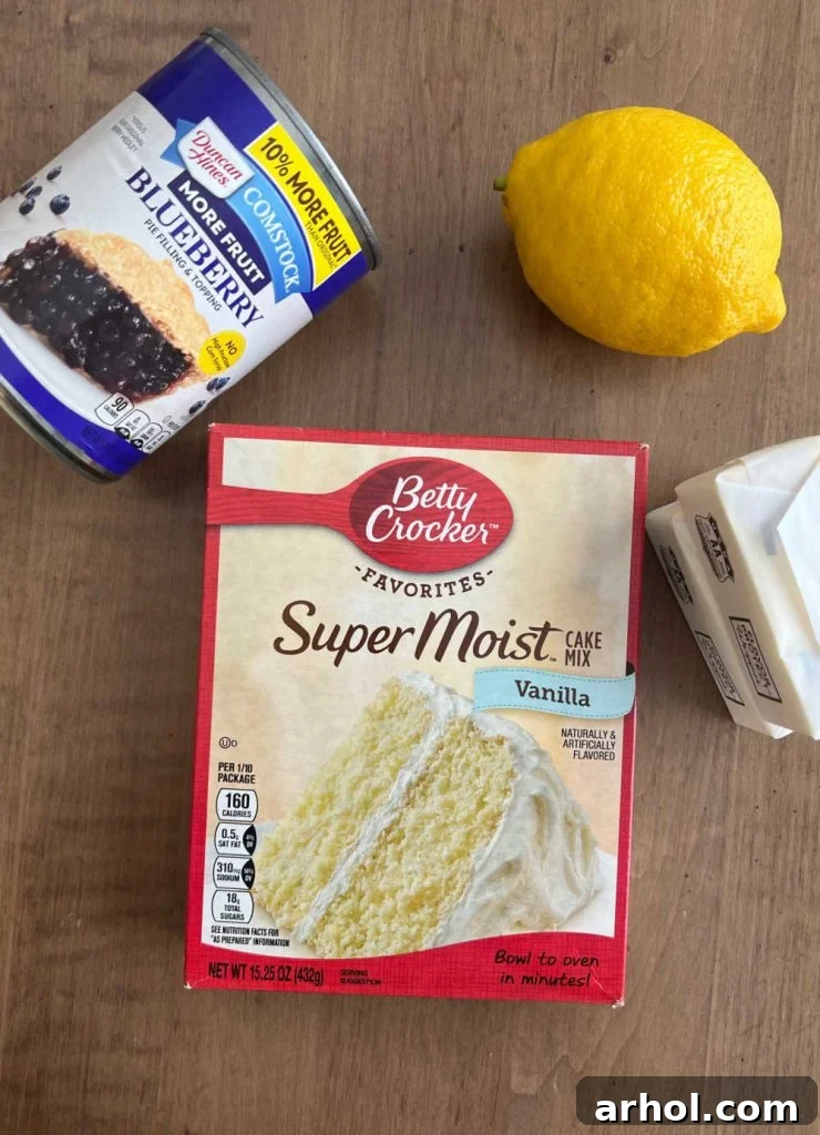 Box of vanilla cake mix, two cans of blueberry pie filling, and butter sticks with a lemon on a rustic wooden table, ready for baking.