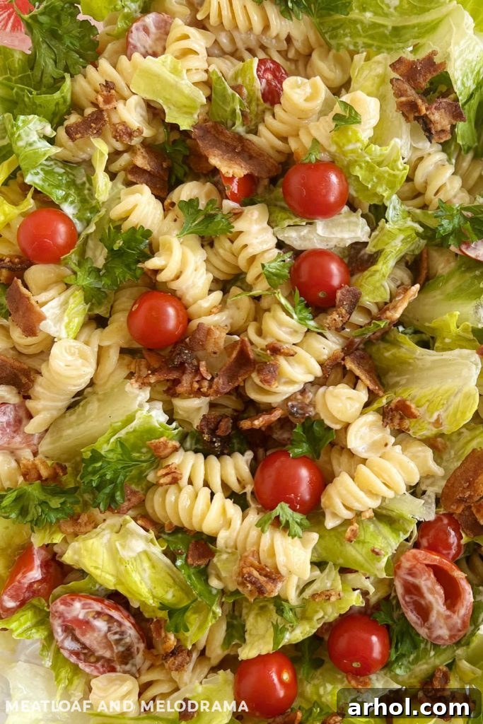 Perfect BLT Pasta Salad 7 Close-up shot of creamy BLT pasta salad featuring rotini, crispy bacon, fresh romaine lettuce, and halved cherry tomatoes, invitingly displayed.
