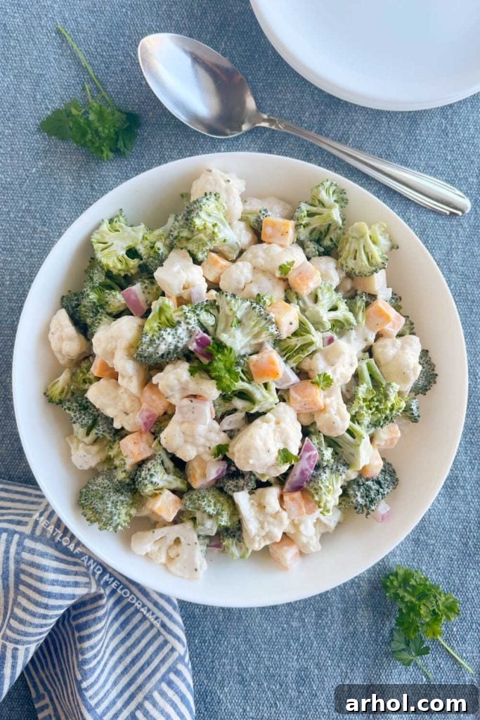 Beautifully presented broccoli cauliflower salad in a pristine white serving bowl on a rustic wooden table, ready to be enjoyed