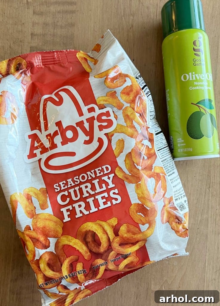 Bag of Arby's frozen curly fries next to a bottle of olive oil spray, essential ingredients for air frying.