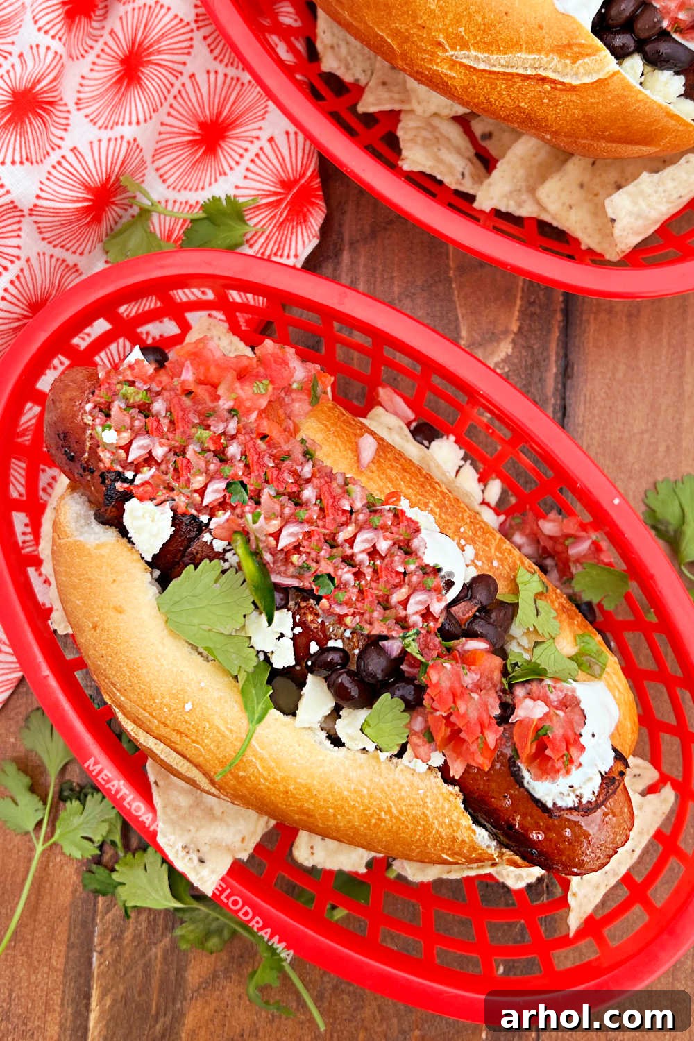 Authentic Sonoran Hot Dogs Blackstone Griddle Style 2 Sonoran hot dogs with crispy bacon, fresh pico de gallo, Cotija cheese, black beans, and cilantro, artfully arranged on a rustic wooden table.