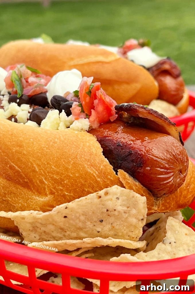 Authentic Sonoran Hot Dogs Blackstone Griddle Style 6 Fully cooked Sonoran hot dogs with crispy bacon, displayed over a bed of tortilla chips in a basket, ready for toppings.