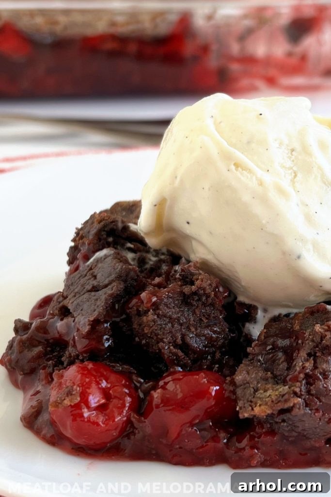 slice of chocolate dump cake with cherry pie filling and vanilla ice cream on top
