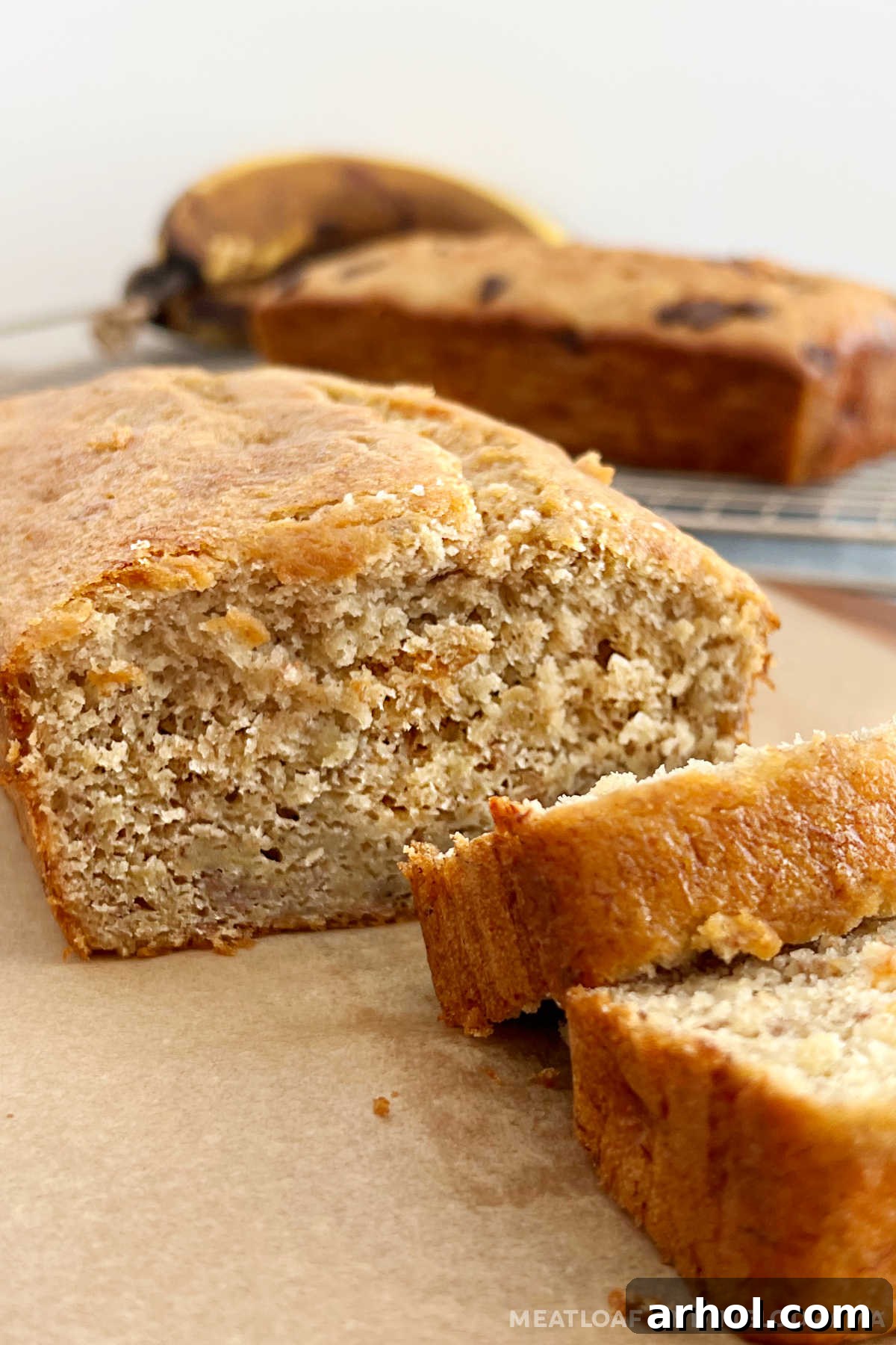 Easy cake mix banana bread sliced on a wooden table, showing its moist texture and golden-brown crust.