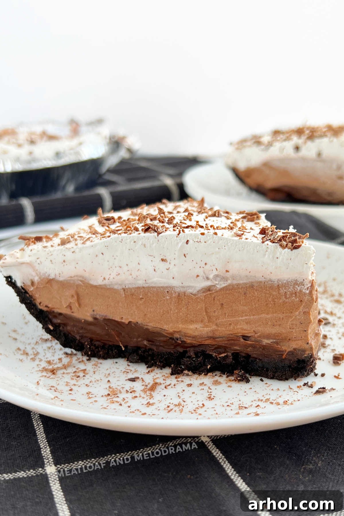 Delicious slice of No Bake Chocolate Pudding Pie with layered instant jello pudding and cool whip, garnished with chocolate shavings, served on a white plate
