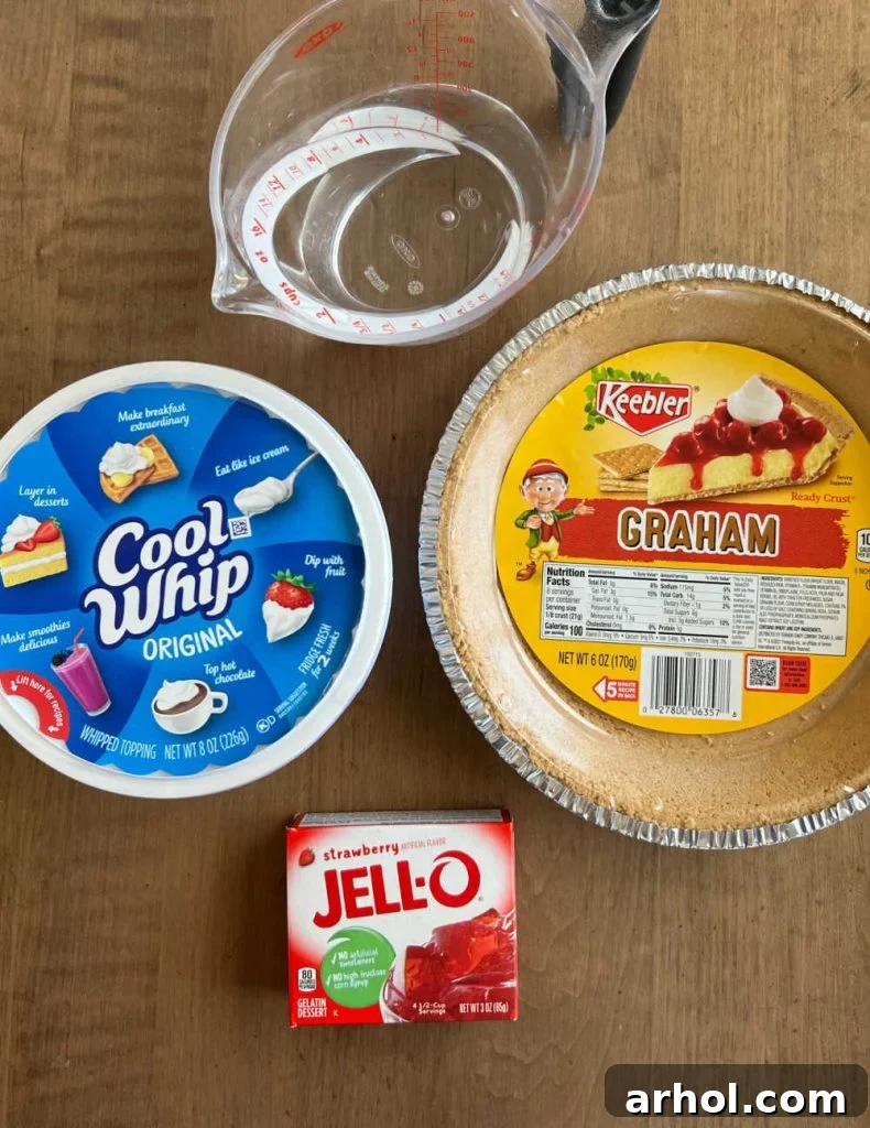 Essential ingredients for No Bake Strawberry Jello Pie: a box of strawberry Jello, Cool Whip, water, and a ready-made graham cracker crust.