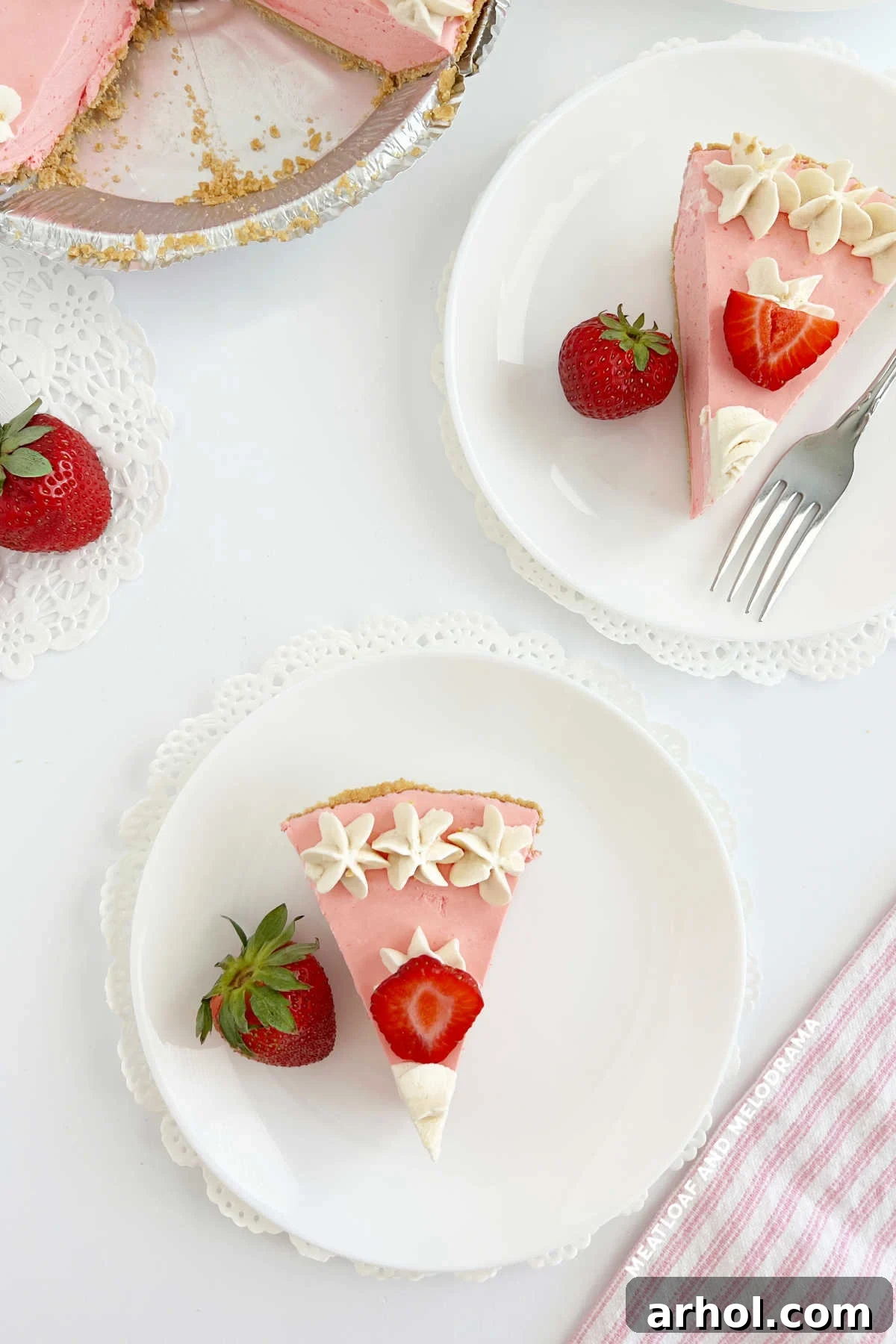 Multiple slices of No Bake Strawberry Jello Cool Whip Pie, adorned with fresh strawberries, arranged on a table for serving.